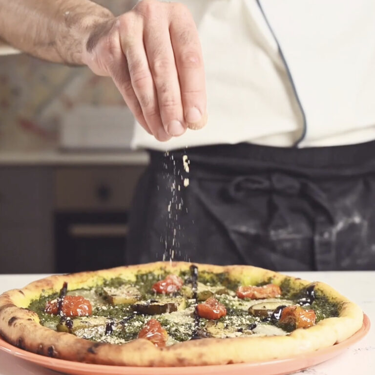 chef sprinking nutritional yeast onto a gluten free pizza